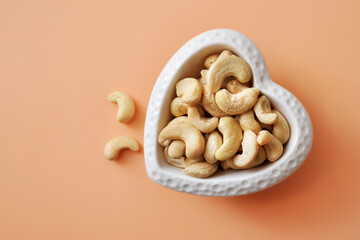 Cashew nuts in a heart-shaped plate. A symbol of healthy food
