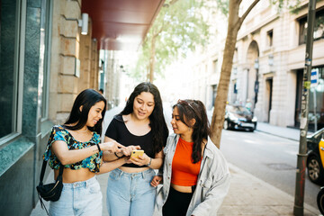 Three young women walking and hanging out on a comercial street of a big city