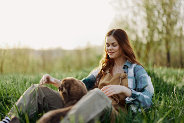 Woman game with her dog in nature smiling and lying on the green grass in the park, happy healthy relationship between mistress and pet