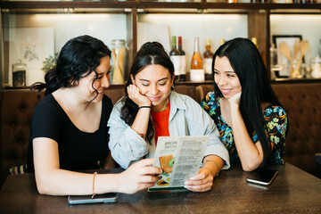 Three young women looking at a menu in a restaurant