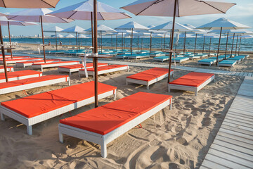Beautiful empty beach with sun umbrellas and sunbeds. Perfect summer vacation destination. Straw...