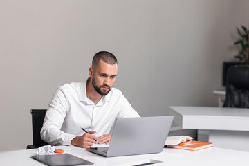 Fototapeta na wymiar handsome man in bright office behind laptop