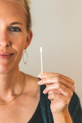 Obraz premium blonde Woman holding covid 19 PCR test swab clean background