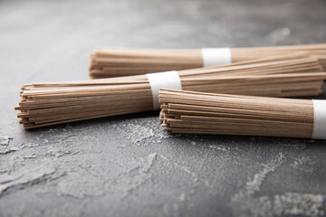 Buckwheat paste on a black cement background. Raw noodles. Ingredients for a gluten-free dish. Dried buckwheat soba noodles. Traditional Japanese food. Healthy food. Place to copy.