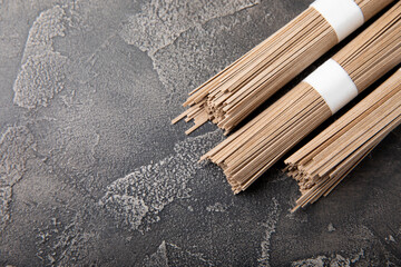 Buckwheat paste on a black cement background. Raw noodles. Ingredients for a gluten-free dish. Dried buckwheat soba noodles. Traditional Japanese food. Healthy food. Place to copy.