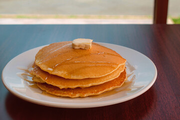 Delicious pancakes with honey and butter on a wooden table in a restaurant