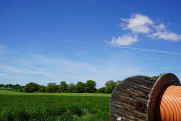 Huge fiber optic cable drums are stored at the edge of the field