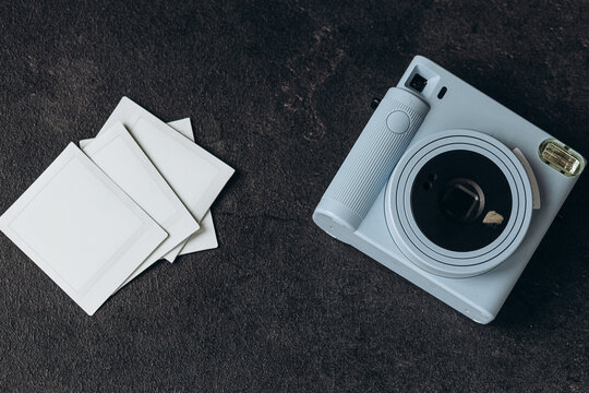 Vintage photo camera on dark background with photo cards. Polaroid camera