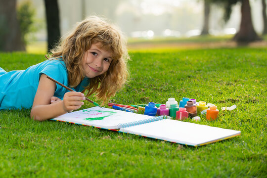 Kids painting in spring nature. Child boy enjoying art and craft drawing in backyard or spring park. Children drawing draw with pencils outdoor.