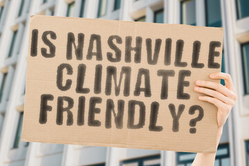 The question " Is Nashville climate-friendly? " is on a banner in men's hands with blurred background. Support. Team. Activist. Urban. Sunset. Carbon. Ecology. Energy