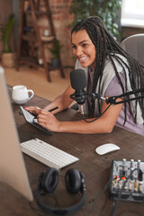 Vertical high angle shot of cheerful attractive young woman sitting at desk in loft room creating content for blog