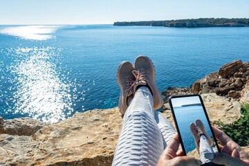 view trekking feet making photography with smart phone on cliff in front of the sea.panoramic landscape vacation concept, foot photography hiking relax enjoy travel vacation,