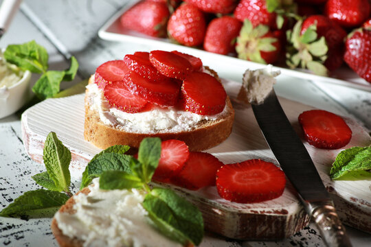 Sandwich with cream cheese and a knife and fresh strawberries, mint. Bread, herbs, fresh  red berries on a white background. Rustic. Background image, copy space