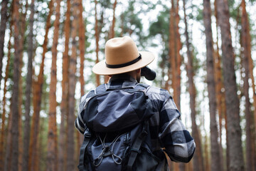 Man tourist with binoculars while hiking in the forest. Hike in the mountains or forest