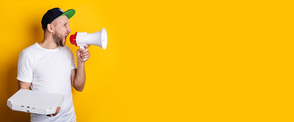 Young man shouting into a megaphone holding packed pizza on a yellow background. Banner