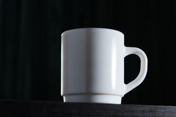 White mug for tea and coffee in on a dark background, close-up