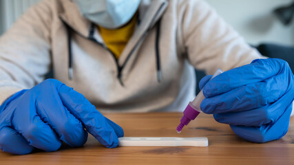 Close-up of man placing the sample into a buffer dropper for coronavirus test