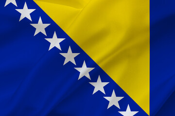 Flag of Bosnia and Herzegovina on waving silk background. Fabric texture.