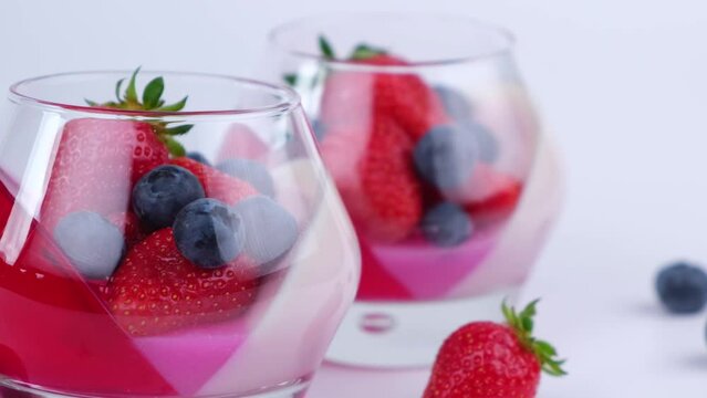 Fruit jelly with strawberries and blueberries in a glass on a white background, a beautiful dessert, pana cotta