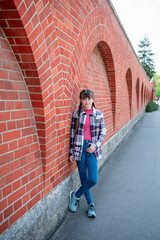 A teenage girl stands near a brick wall. Beautiful brick wall