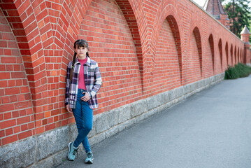 Obraz na płótnie Canvas A teenage girl stands near a brick wall. Beautiful brick wall