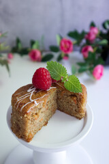 Carrot cake in cutaway decorated with raspberries and mint leaves on a white stand