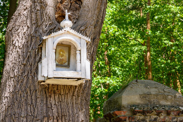Mała drewniana kapliczka zawieszona na drzewie. - obrazy, fototapety, plakaty