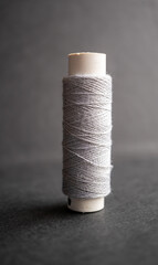 un carrete de hilo de algodón color gris sobre fondo obscuro