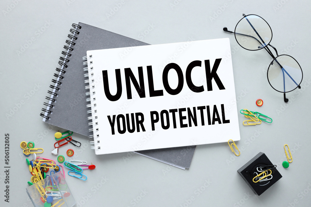 Poster two notebooks on a gray background. text on notebook - unlock your potential