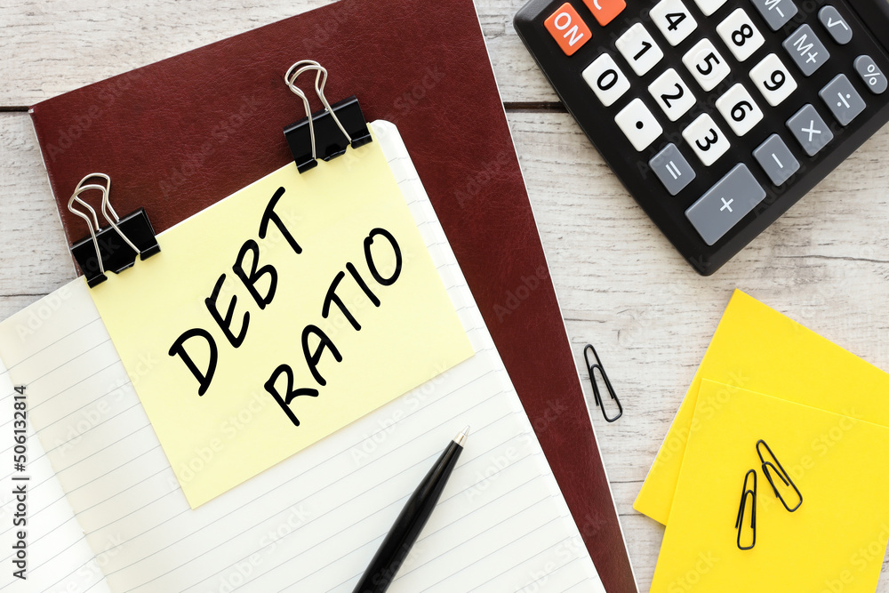 Poster text debt ratio text on yellow note on red notepad near calculator