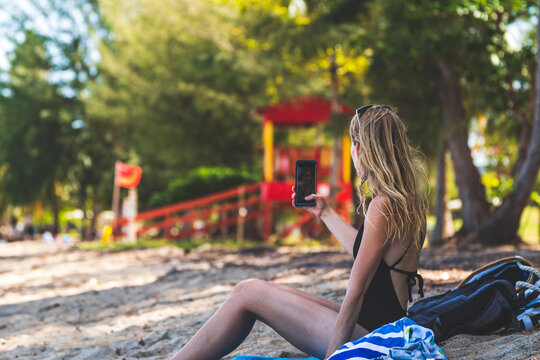Woman taking a picture with smartphone while vacationing on beach