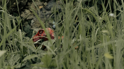 Red Tyrannosaurus-rex or T-rex, dinosaur in tracking mode, camouflaged in plants