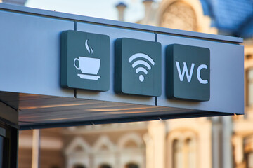The symbol of coffee, WiFi, toilet on the background of a yellow building. Tourism and entertainment concept