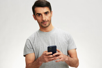 man in a gray t-shirt with a phone communication technology isolated background