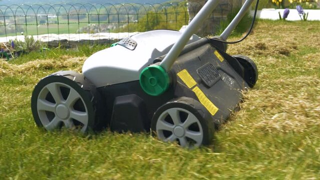 CLOSE UP: Lawn aeration device for soil compaction relief and healthier turf. Spring lawn maintenance and care for grass growth enhancement. Practical gardening machinery for efficiency at landscaping