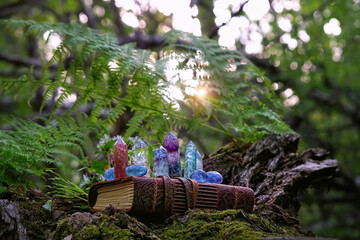 old witch book and quartz minerals on natural green forest background. Gemstones for healing Magic...