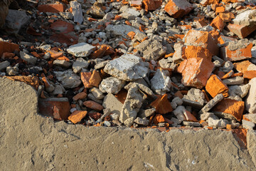 The foundation of a ruined building with fragments of red bricks and an entire wall
