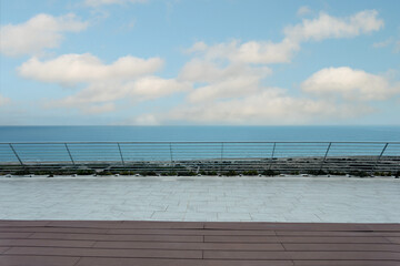 Wooden platform with a chrome railing overlooking the sea.