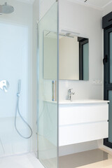 Part of a modern bathroom. A view of a glass shower cubicle and a cabinet with a washbasin. - 506138035