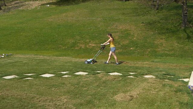 STATIC SHOT: Young female person using lawn aerator at home garden maintenance. Spring backyard garden work for lawn growth enhancement. Practical gardening machinery for efficiency at landscaping.