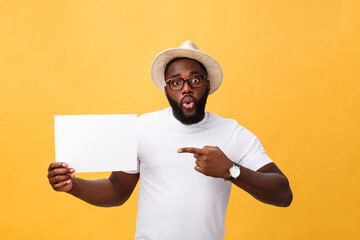 Picture of young smiling african-american man holding white blank board and pointing on it, on...