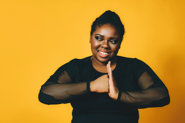portrait of a smiling confident black woman with fist on palm together on yellow background studio