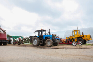 Obraz premium Agricultural machinery, tractors and equipment outdoors, near the garage, ready to work in the field.