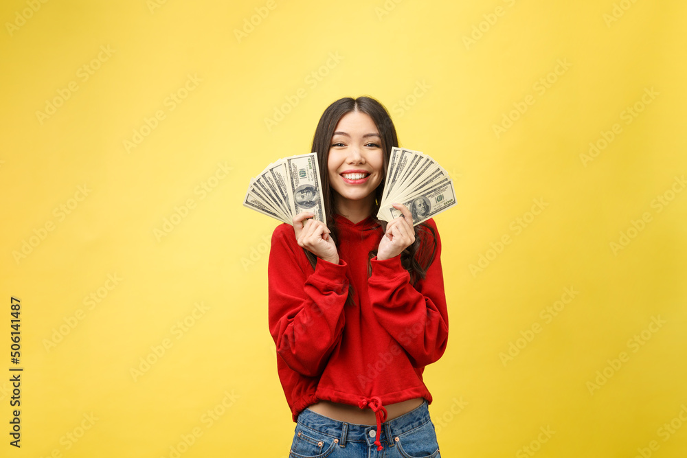 Wall mural Closeup of young beautiful woman with us dollar money in hand over yellow background, with copy space