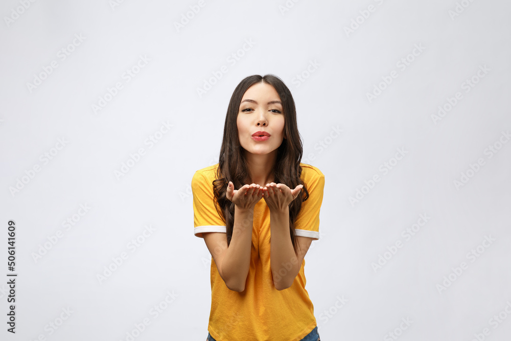 Wall mural Portrait of a young cute woman blowing kiss at camera isolated on white background