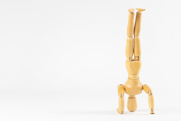 三点倒立している木製デッサン人形