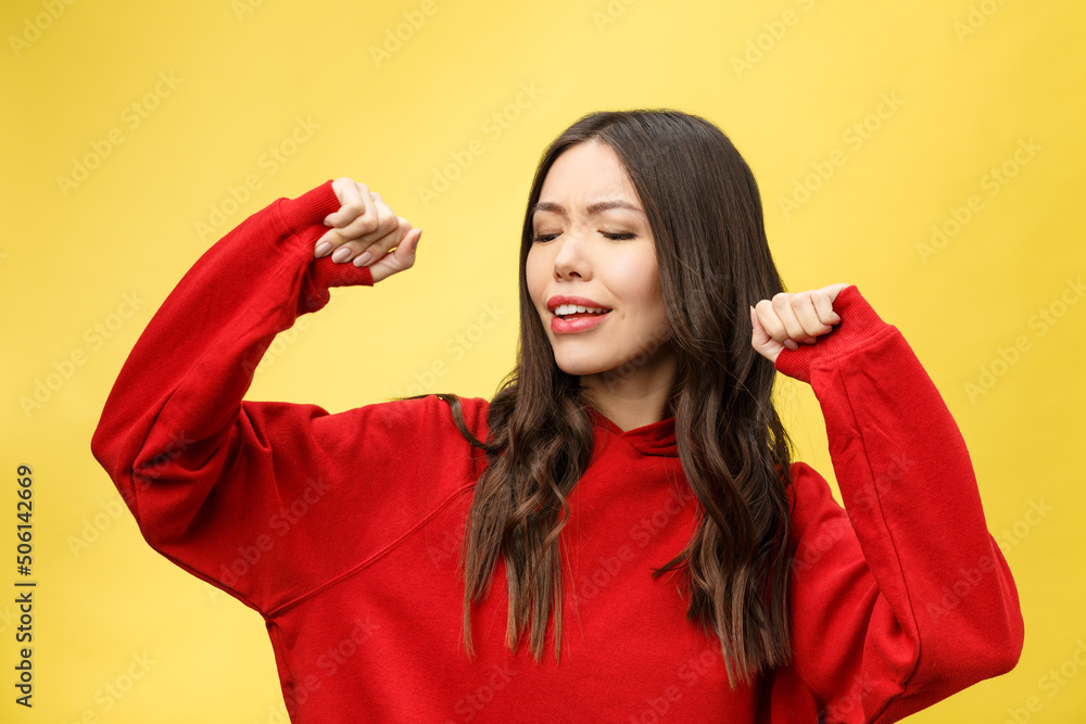 Sticker Portrait of a happy asian woman dancing isolated over yellow background