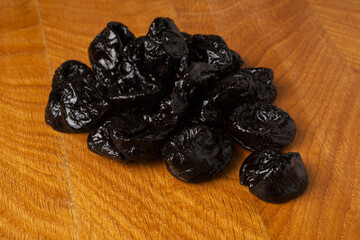 Dried dried prunes in a heap on a wooden board