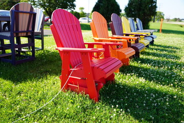 Colorful wooden lawn chairs are set up outside to be sold 