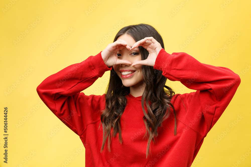 Wall mural portrait smiling young woman making heart sign with hands.